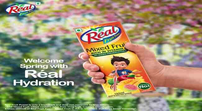In the image showing a hand who holding a packet of real juice