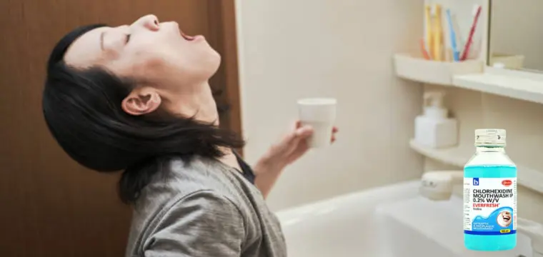 A woman in their bathroom using Chlorhexidine mouthwash ip 