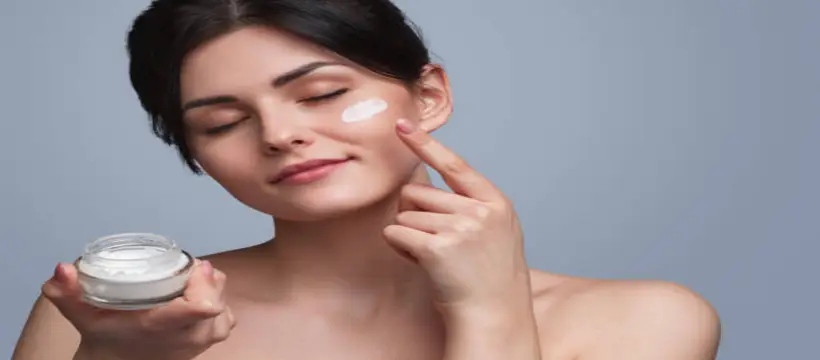 A woman apply cream on her face with happiness
